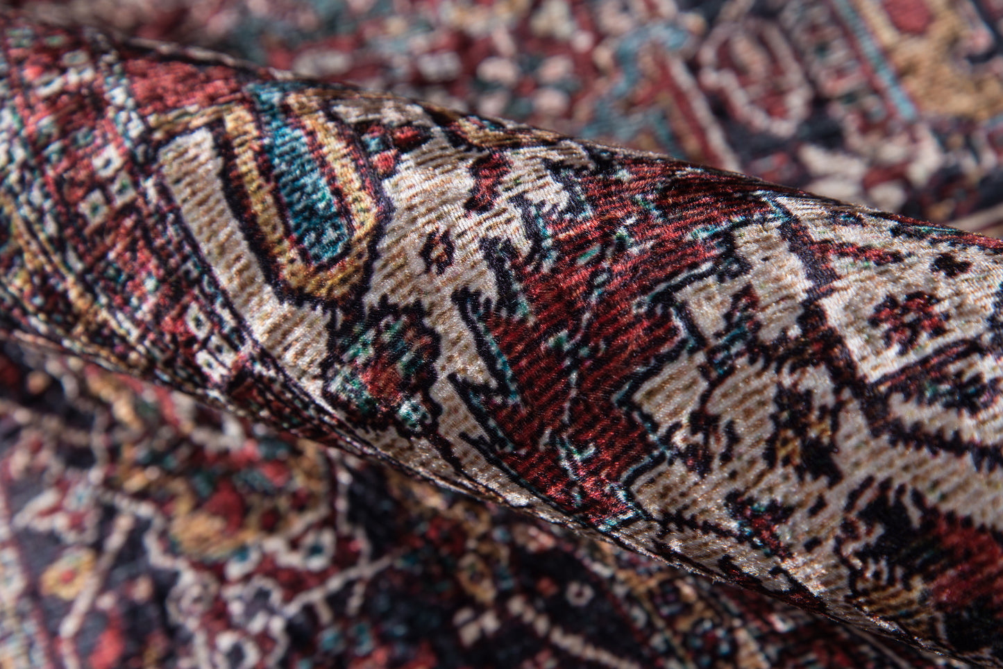 Rolled Persian-style rug with red, ivory & teal floral patterns and dense oriental motifs.