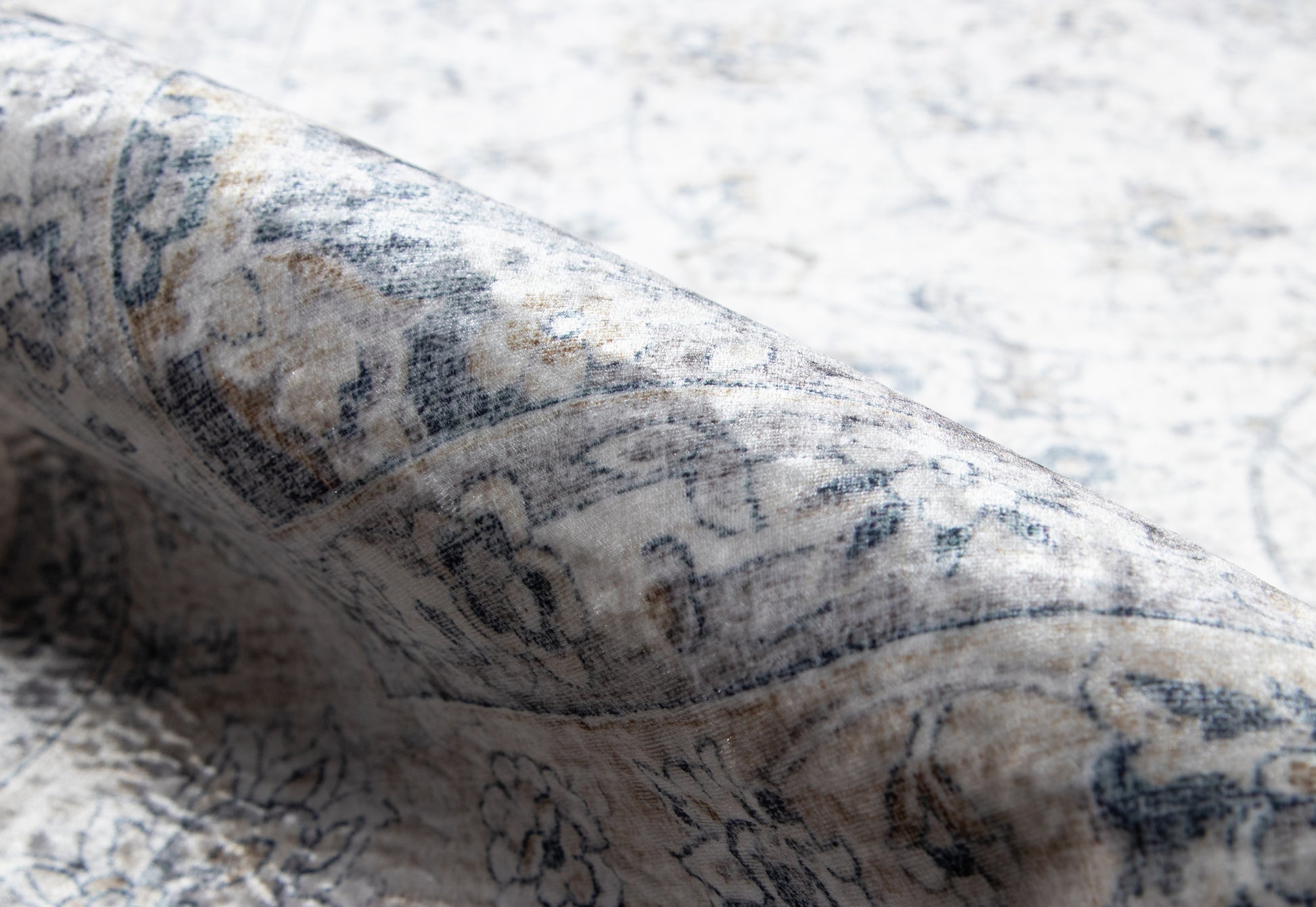 Close-up of gray and ivory Persian-style runner rug with folded corner, floral border and soft textured pile.