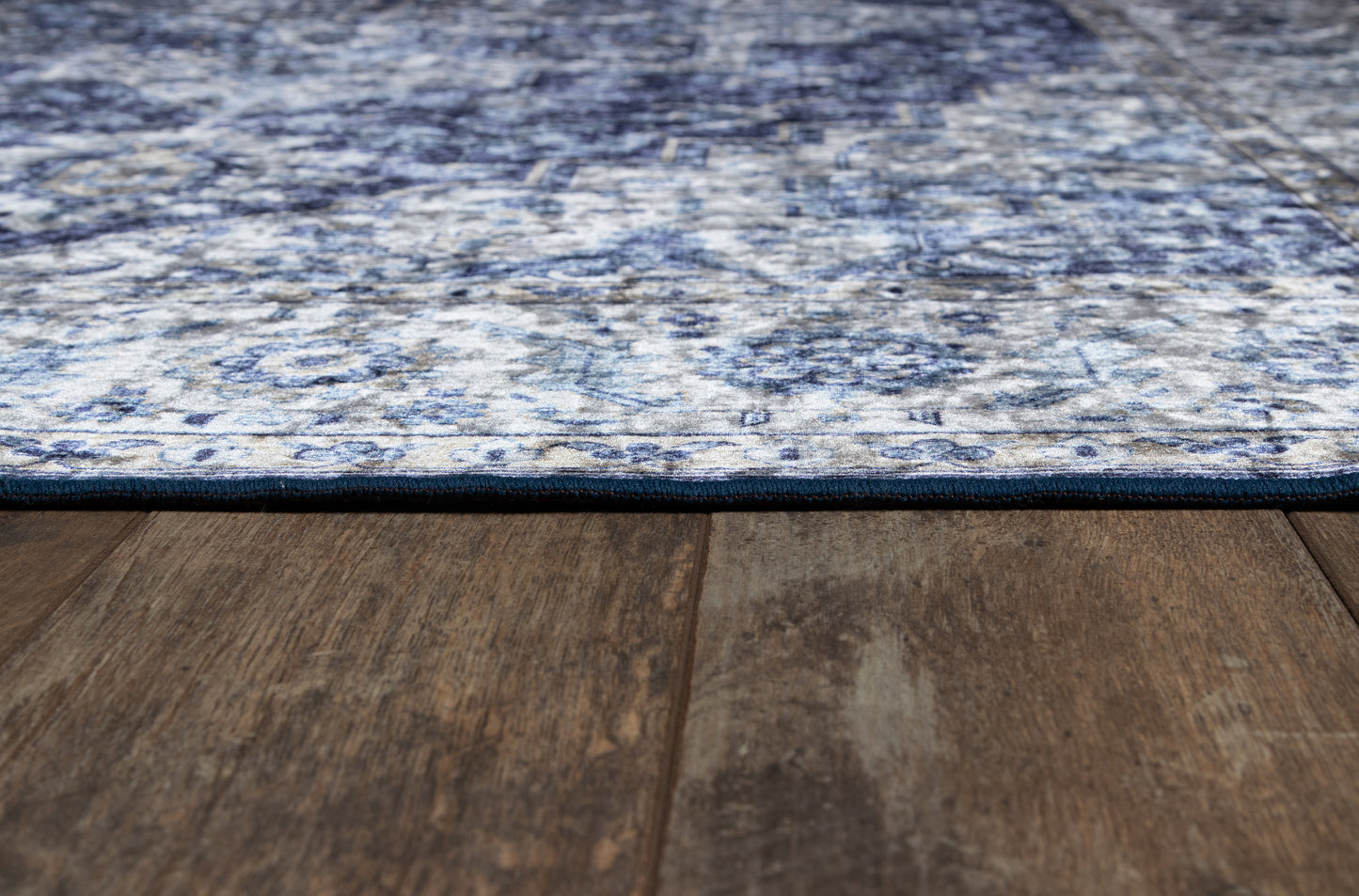 Rectangular blue and white patterned area rug laid over dark wood flooring.