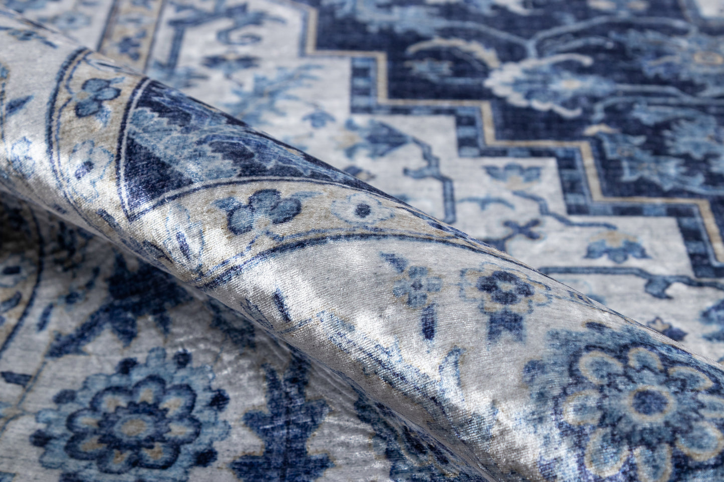 Blue and ivory oriental rug with floral motifs and zigzag border, folded corner.