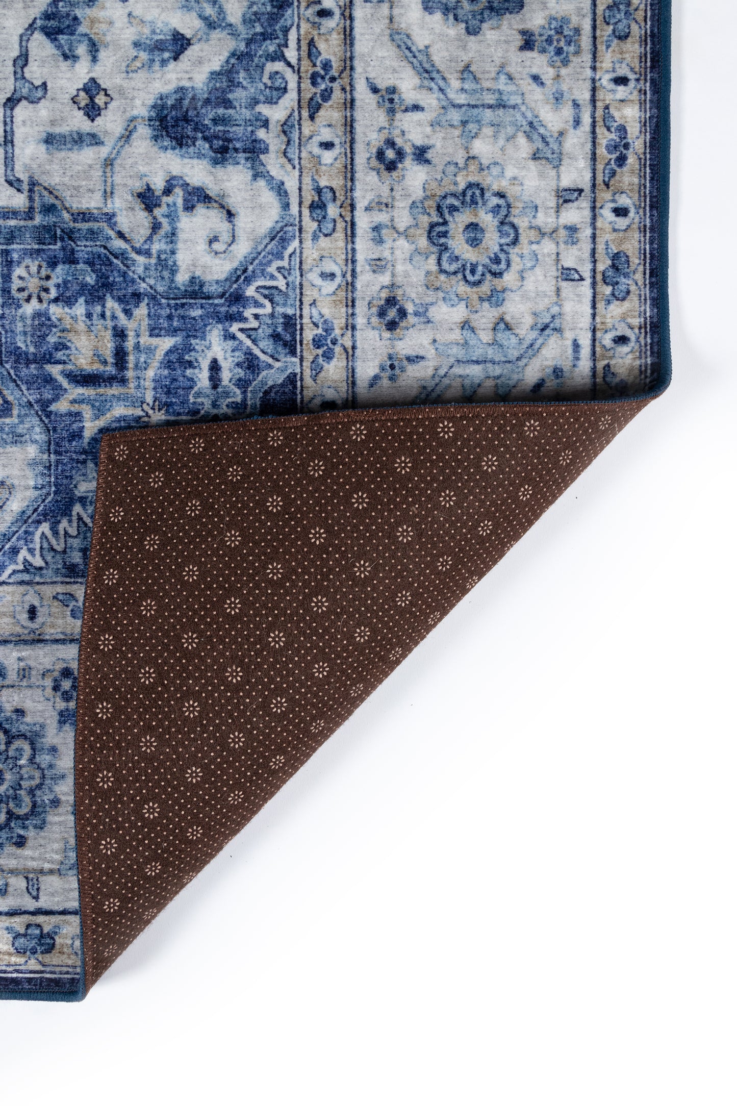 Blue and white oriental rug with floral medallion; corner folded to show brown dotted underside.