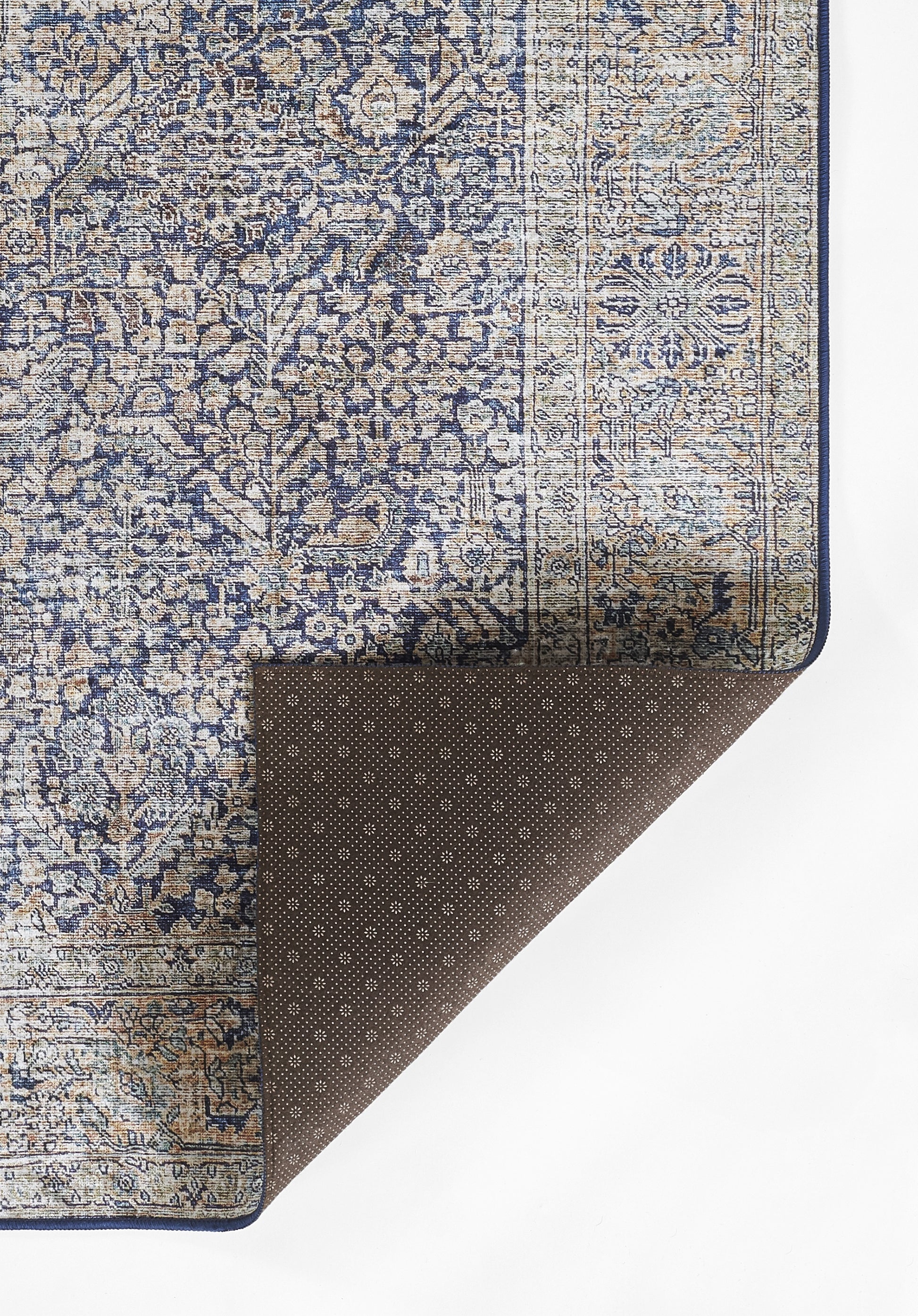 Blue & beige oriental rug with floral pattern & border; brown dotted underside folded at corner.