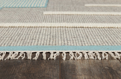 Light gray woven rug with blue stripe accents and white fringe, spread over dark wooden floor.