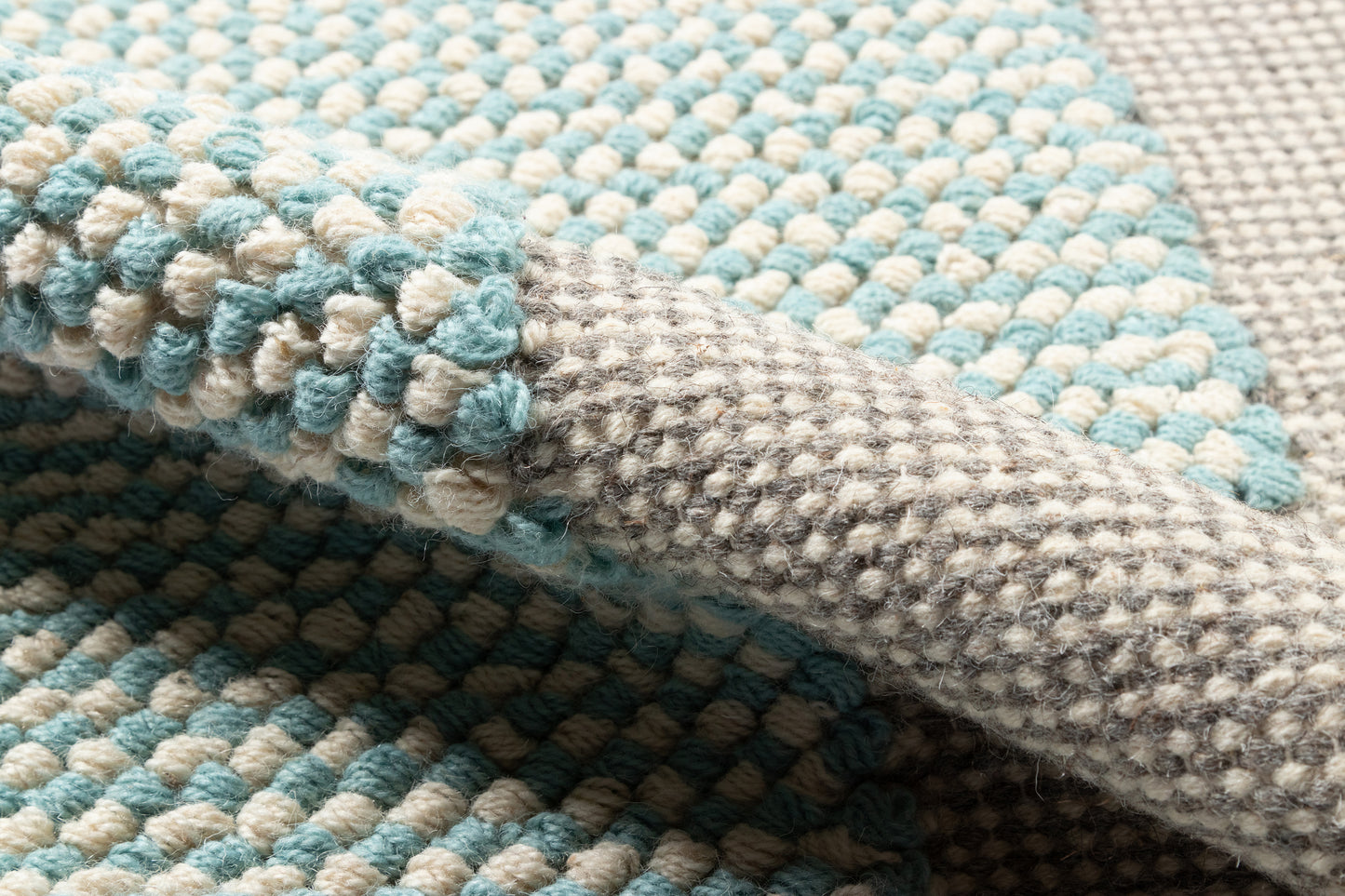 Chunky looped rug in aqua blue and heather gray, close-up woven texture, modern cozy area rug.