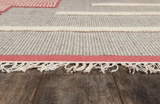 Gray woven rug with cream stripes, red border, and fringed edge on dark wooden floor.