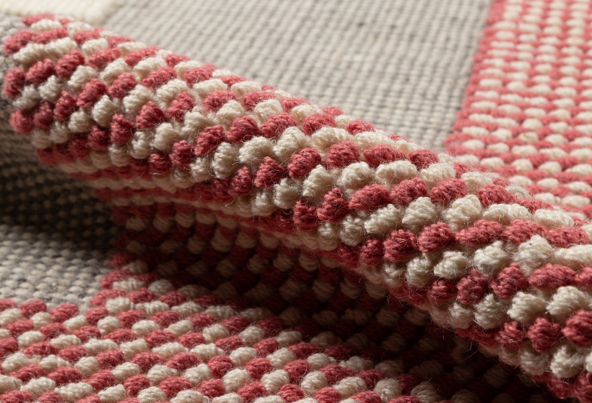 Close-up of pink and cream chunky-loop woven rug texture with a grid pattern.