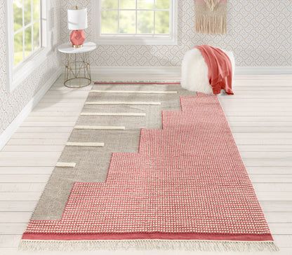 Two-tone woven rug runner with stepped zigzag border in beige and pink, fringed ends, in a bright living room.