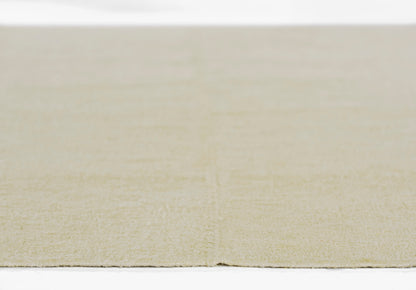 Ivory beige flatweave rug with soft, textured surface and slightly frayed edge.