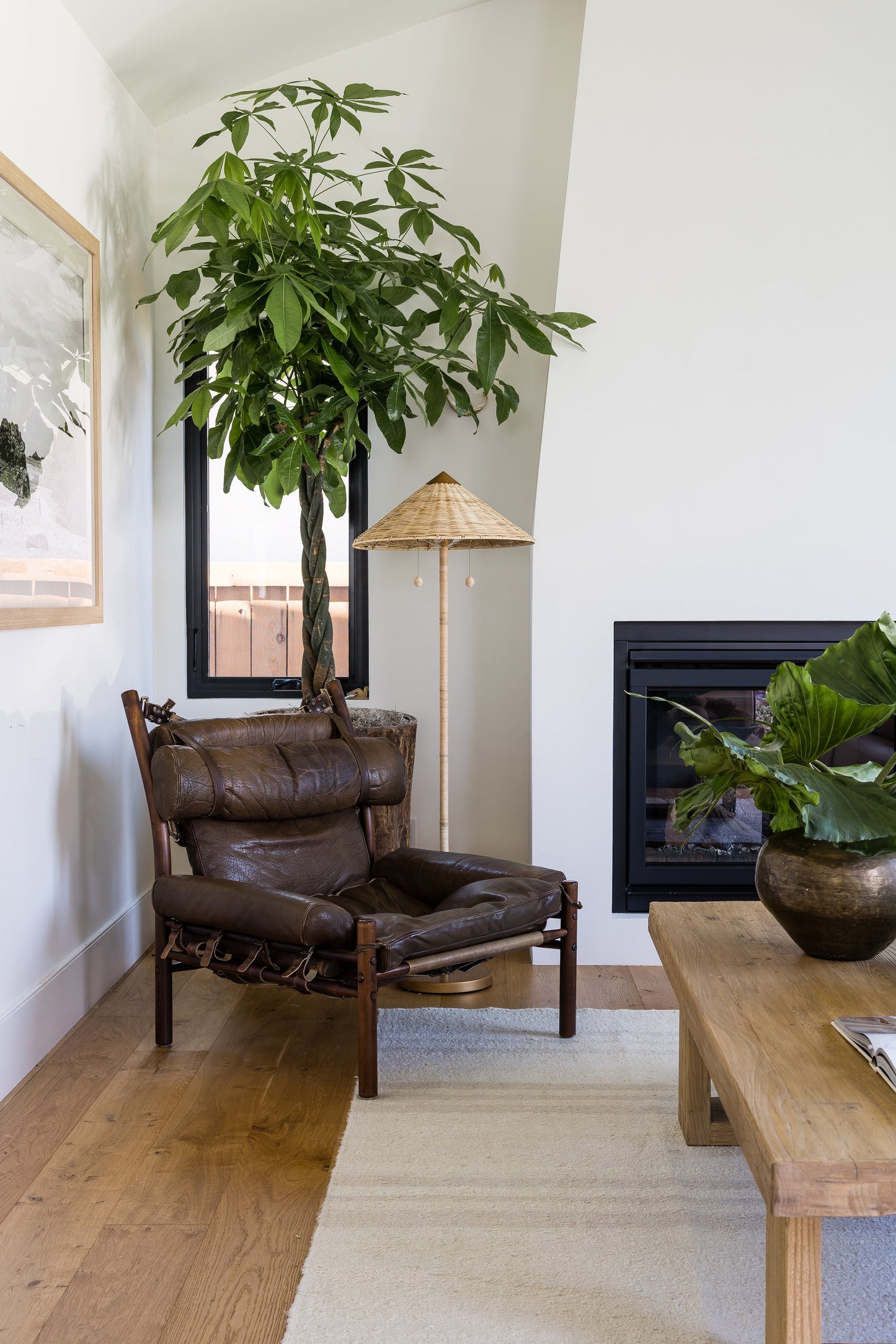 Muted Stripe area rug (8' x 11') on an oak floor in a living room, with a brown leather lounge chair, a large leafy ficus, a woven cone lamp and a coffee table.