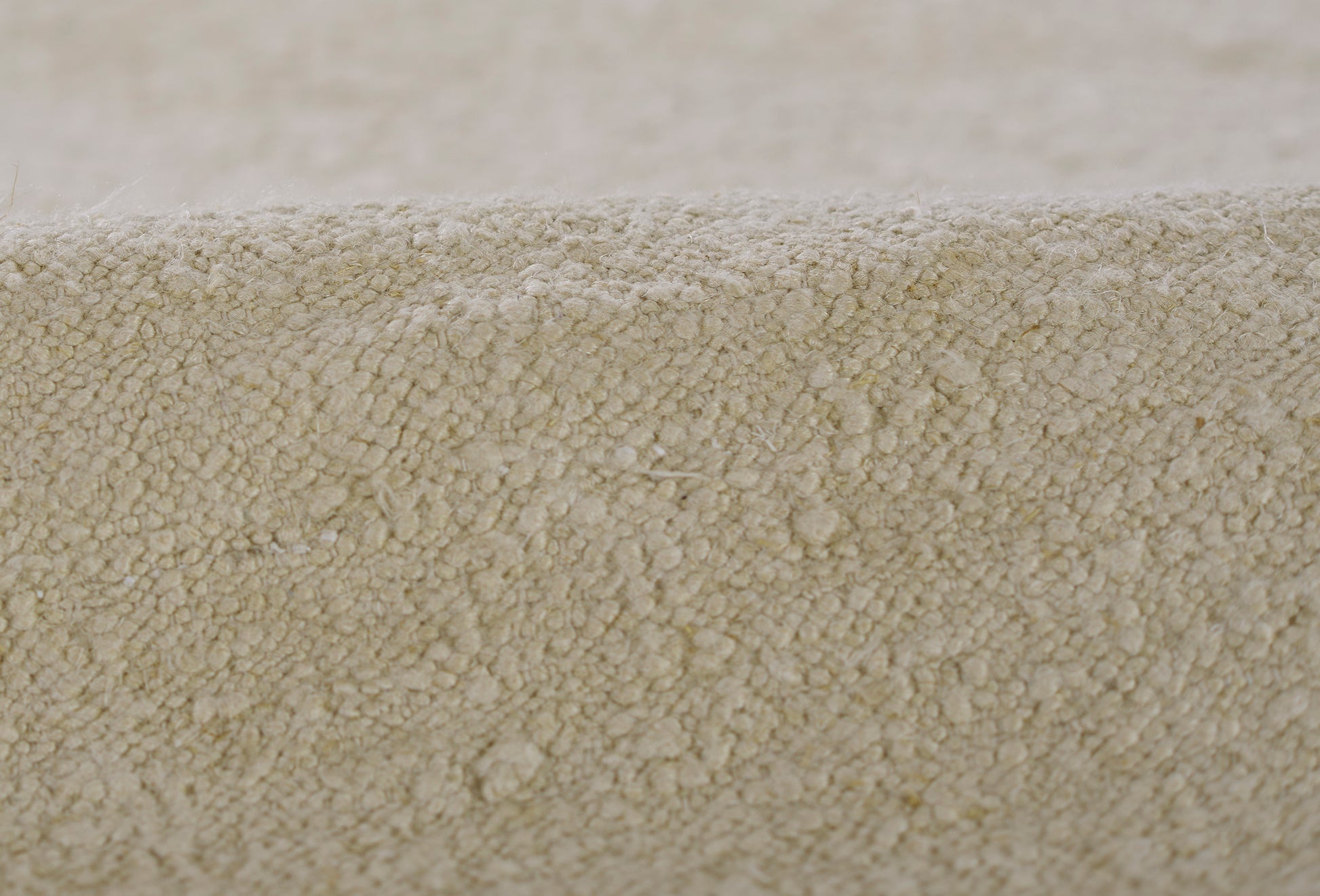 Beige textured rug close-up with plush boucle pile and rolled edge.