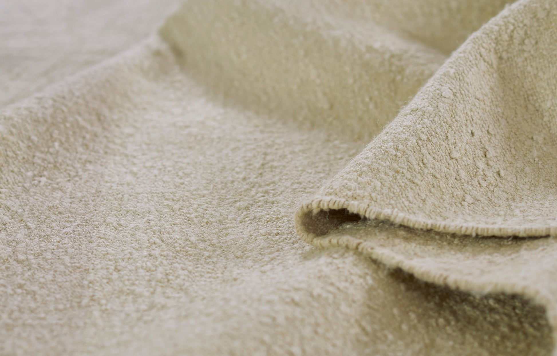 Beige muted-stripe rug close-up showing plush pile and a folded edge.