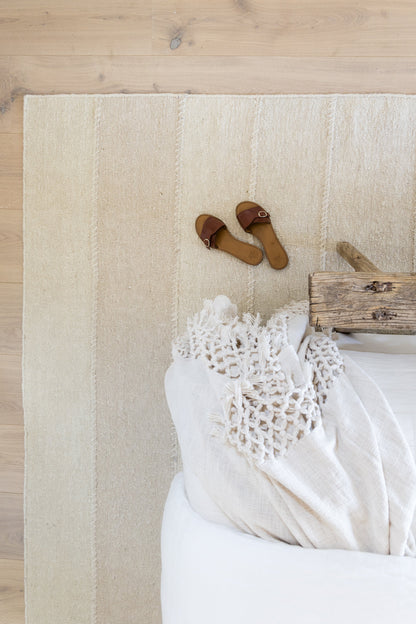 Beige striped area rug on light wood floor, 5' x 8'.