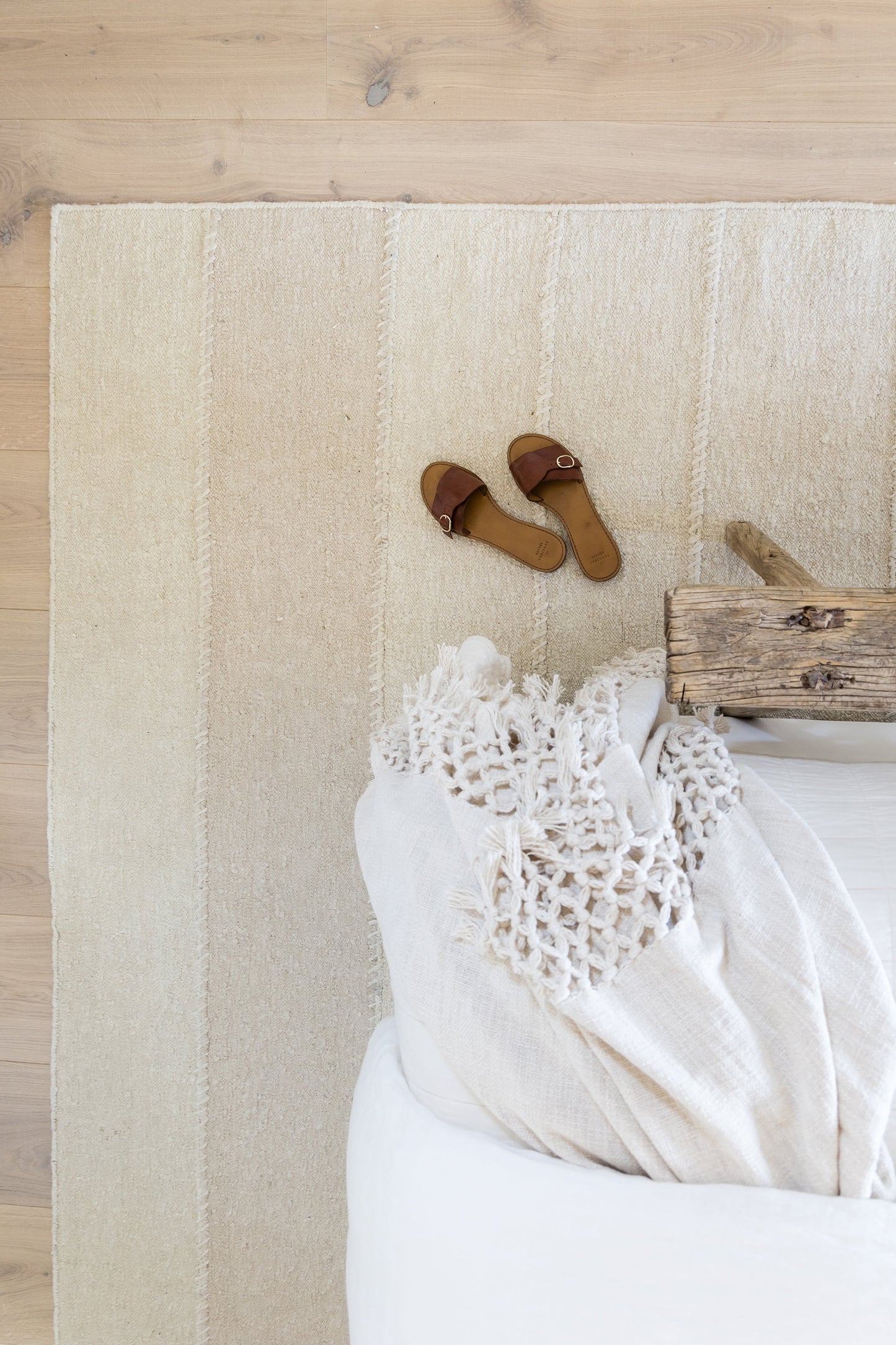 Beige striped rug on natural wood floor.