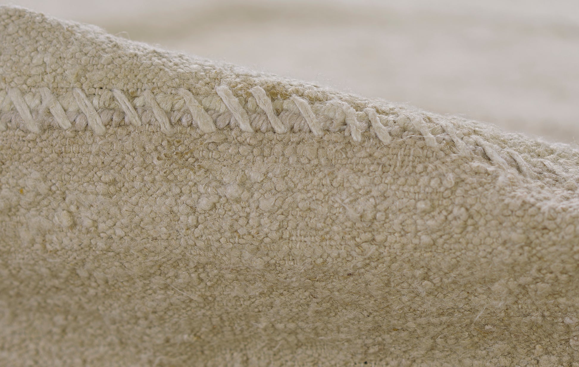 Beige boucle rug close-up with a stitched edge.