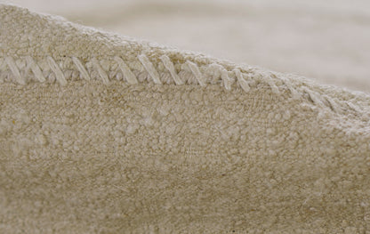 Beige boucle fabric close-up with chunky seam stitching; cozy woven throw or rug texture.