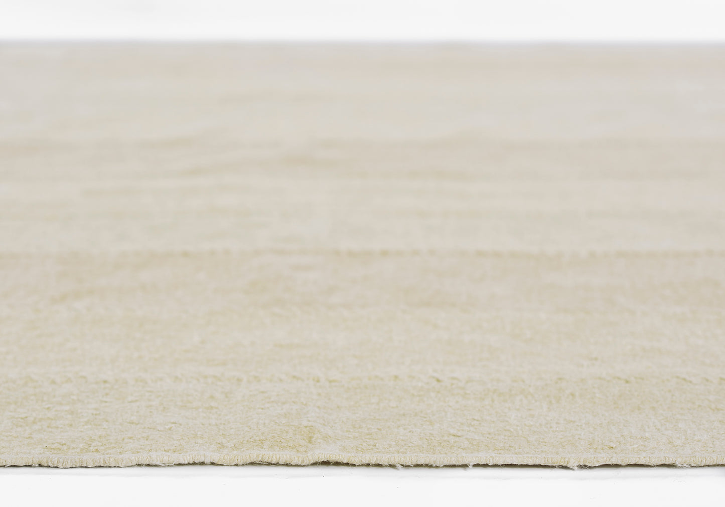 Beige flat-weave rug with cream tones, subtle texture and fringe along the edge.
