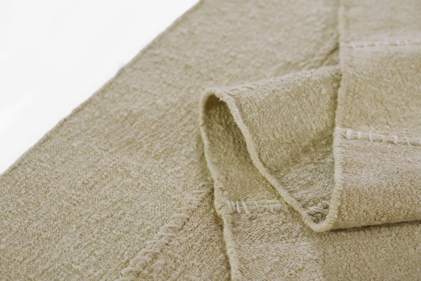 Beige rug close-up showing plush pile and stitched edge