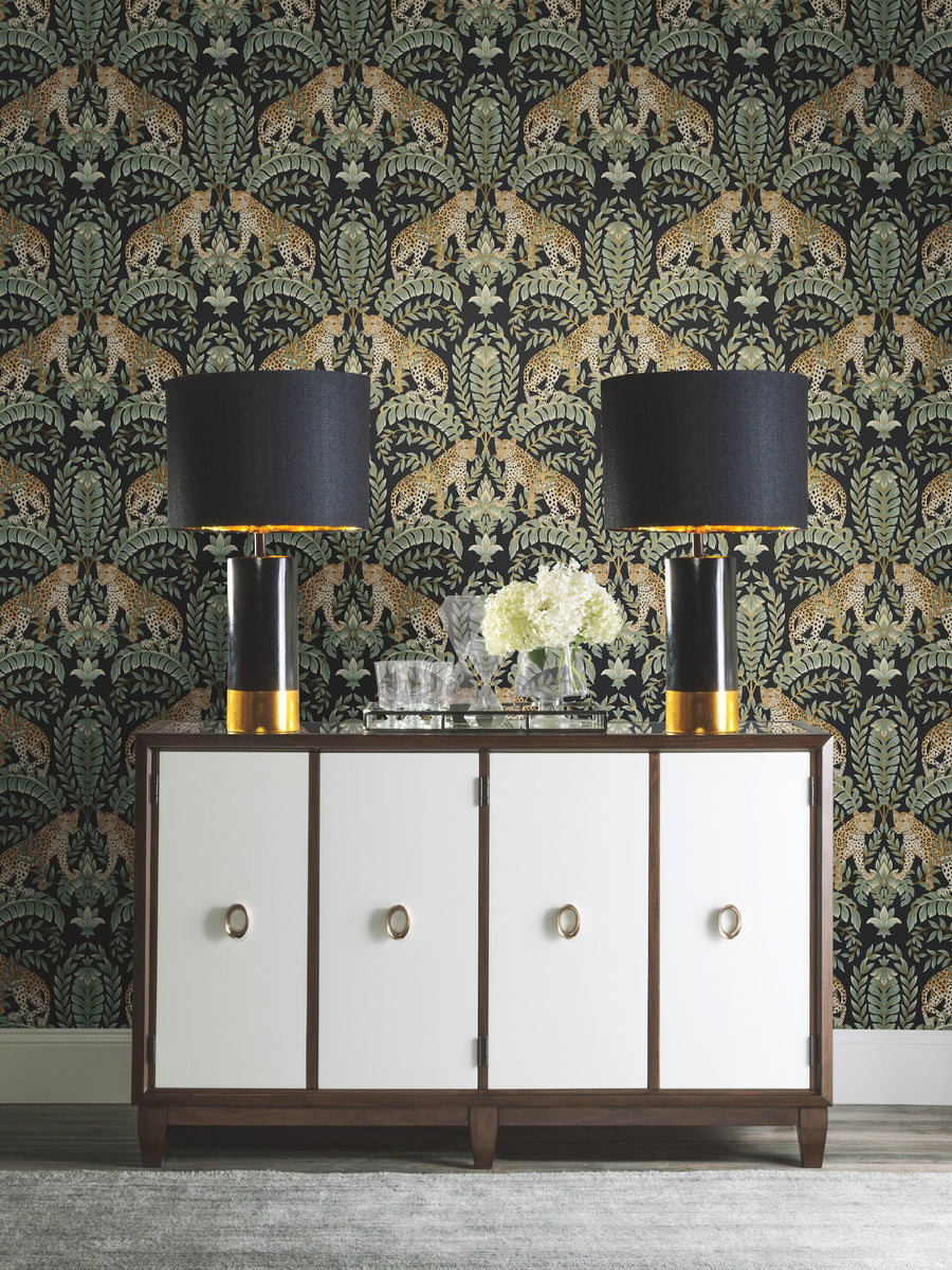 Black and green jungle wallpaper with repeating leopard figures, large acanthus leaves, leafy botanical branches, and decorative floral elements for a dramatic traditional interior.