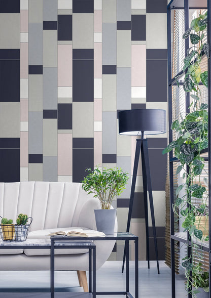 Geometric navy, taupe and blush tiled wall behind a beige sofa, with a coffee table, tripod floor lamp and potted plants.