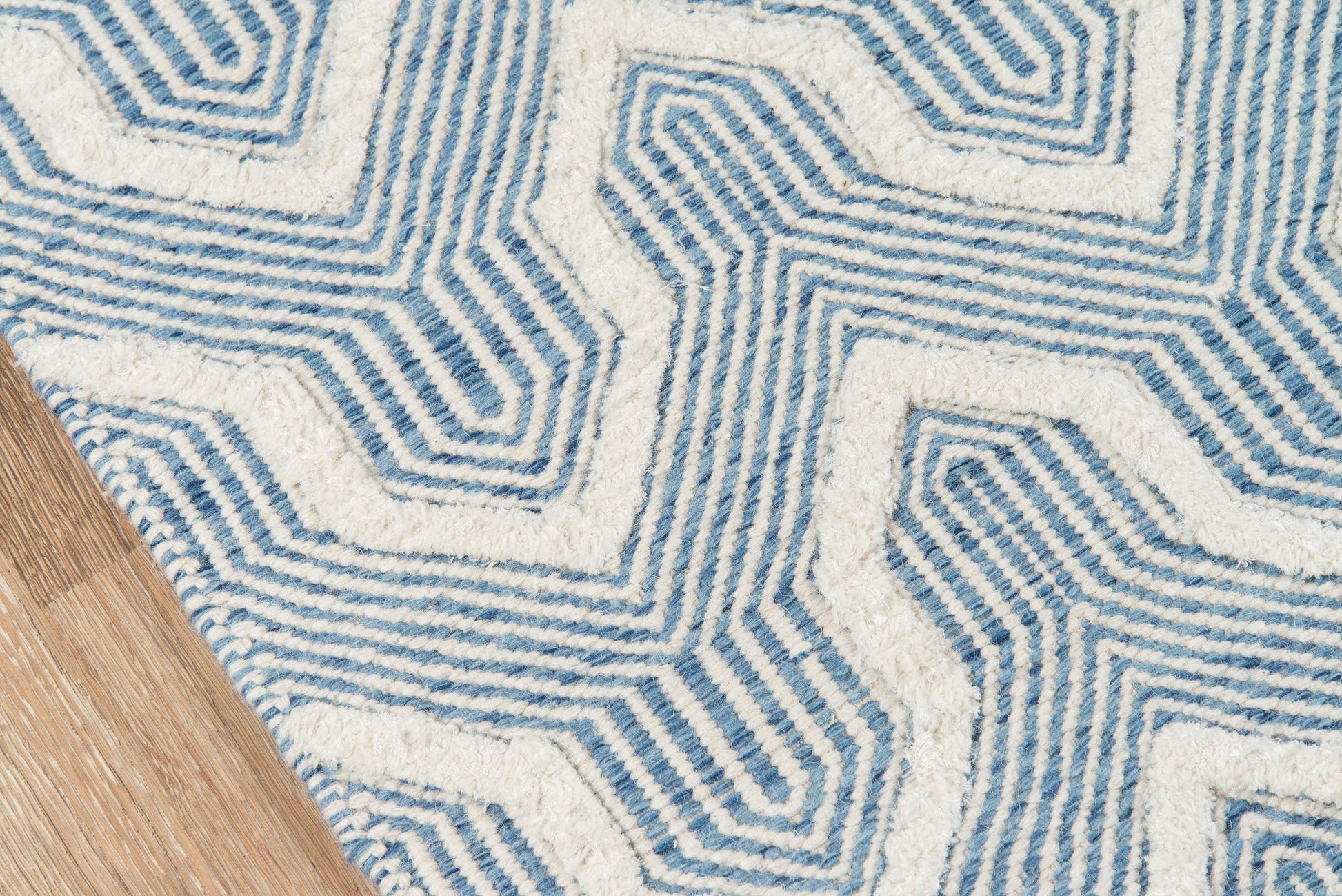 Blue and white geometric area rug with labyrinthine pattern on wooden floor