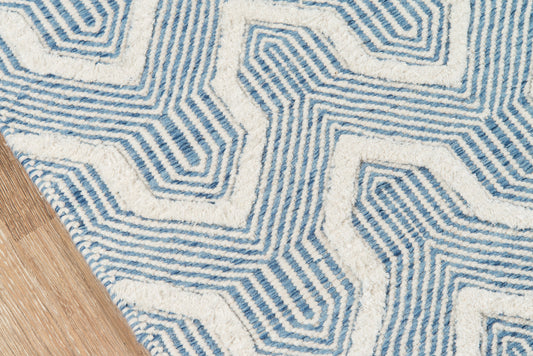 Blue and white geometric area rug with labyrinthine pattern on wooden floor