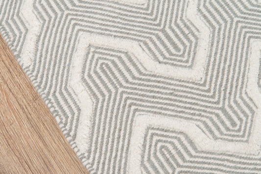 Grey geometric area rug with maze-like linear pattern on light wood floor; modern, low-pile.