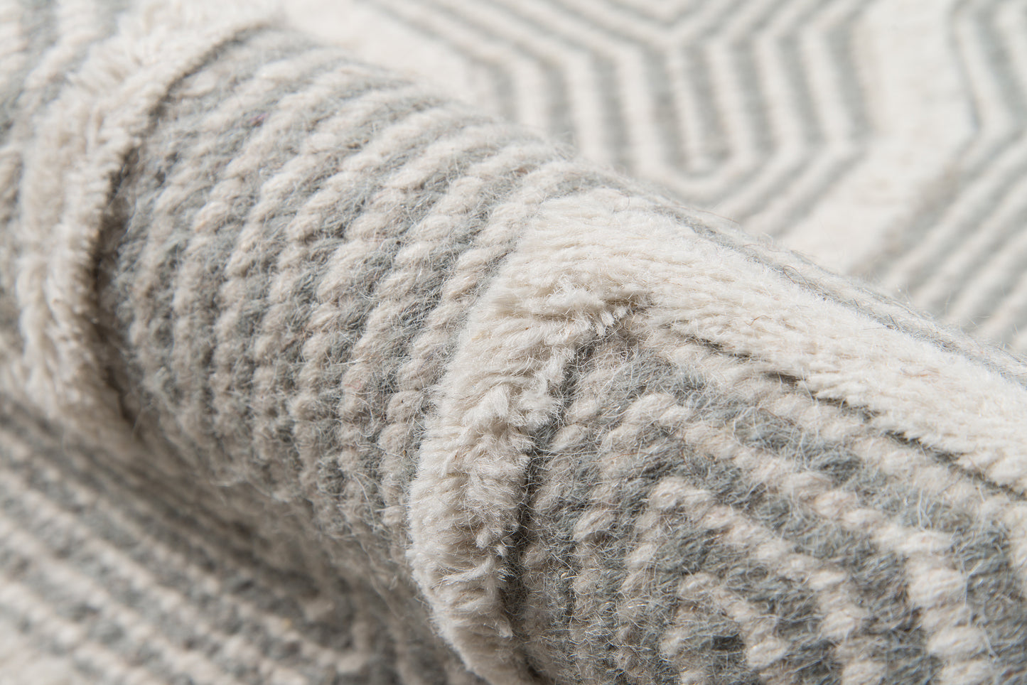 Close-up of a soft gray and ivory woven rug with raised geometric pattern and plush pile.