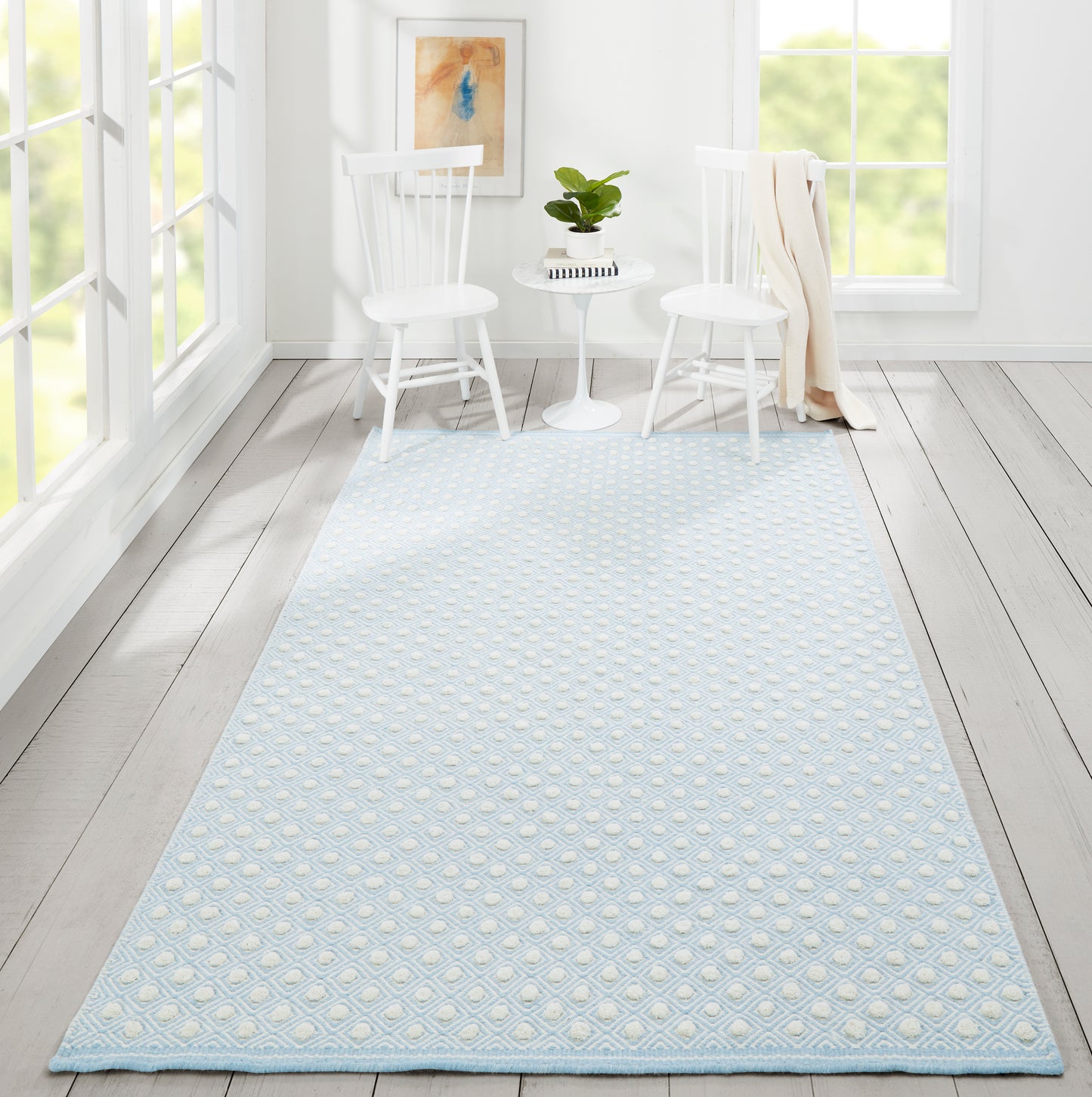 Soft light-blue textured rug with raised dot pattern in a bright white room beside two white Windsor chairs and a round table.