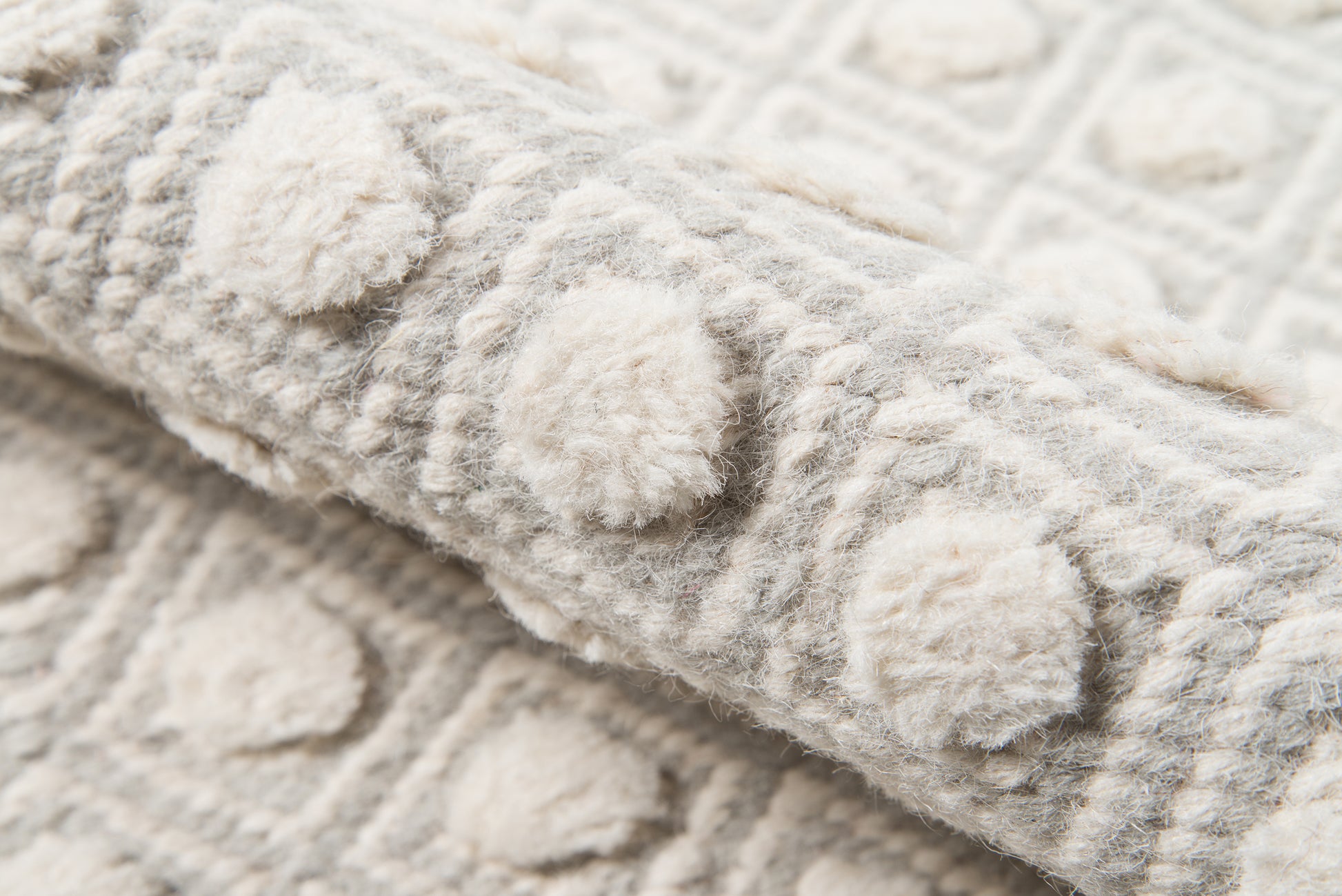 Soft gray and ivory textured rug with circular tufted motifs; plush wool feel for cozy living spaces.