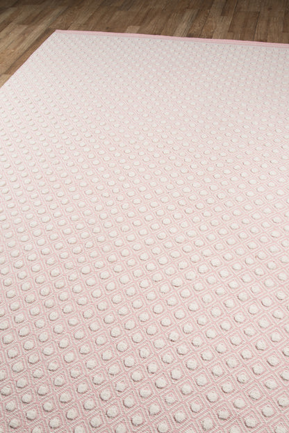 Soft pink rug with a raised dot grid in square outlines on a wood floor.