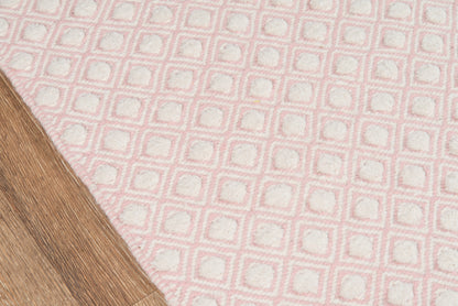 Soft pink tufted rug with white square grid pattern on a light wood floor.