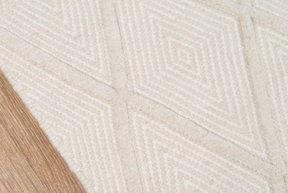 Beige textured rug with white geometric diamond pattern; light wood flooring visible at edge.
