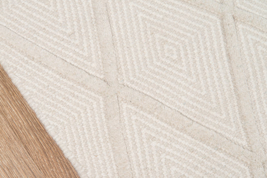 Beige geometric rug with diamond pattern in a textured weave; cream tones, modern style with light wood floor edge.