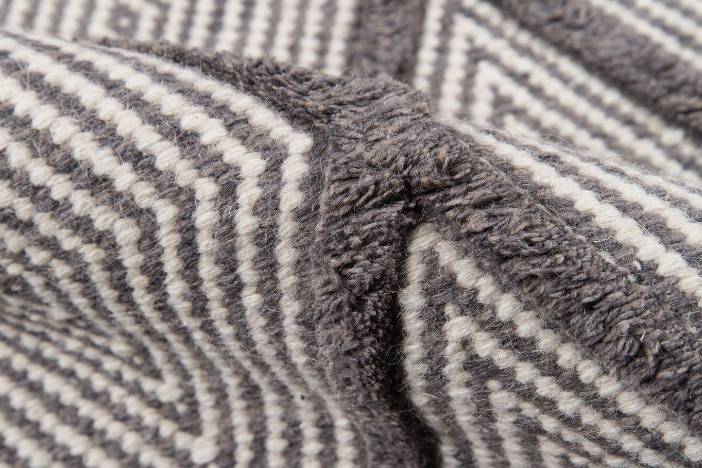 Close-up of a gray and white striped plush blanket with soft, fuzzy texture.