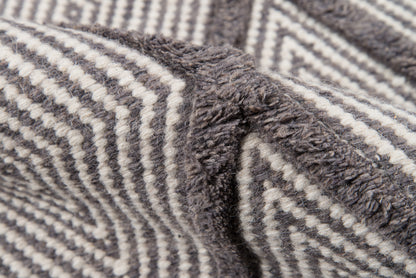 Close-up of a gray and off-white striped plush fabric, likely a cozy blanket or throw, with textured fibers.