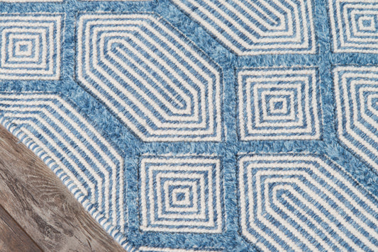 Blue and white geometric rug with nested square motifs on a wooden floor.