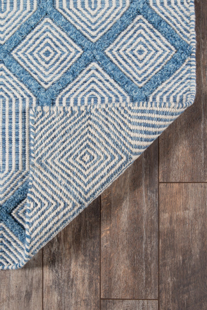 Blue and ivory geometric diamond rug with a woven texture, folded corner on a wood floor.