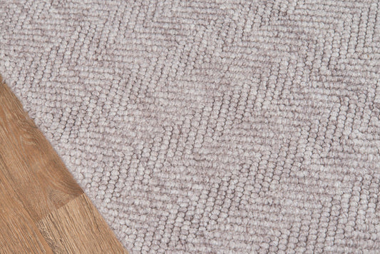 Taupe textured loop-pile rug with grey-beige tones and a wooden floor edge visible.
