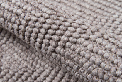 Taupe-gray bouclé rug close-up with chunky looped pile and soft woven texture.
