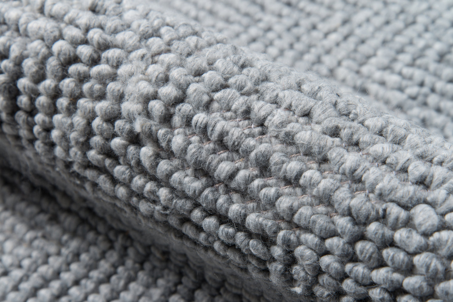 Gray boucle-loop rug close-up with dense plush pile texture.
