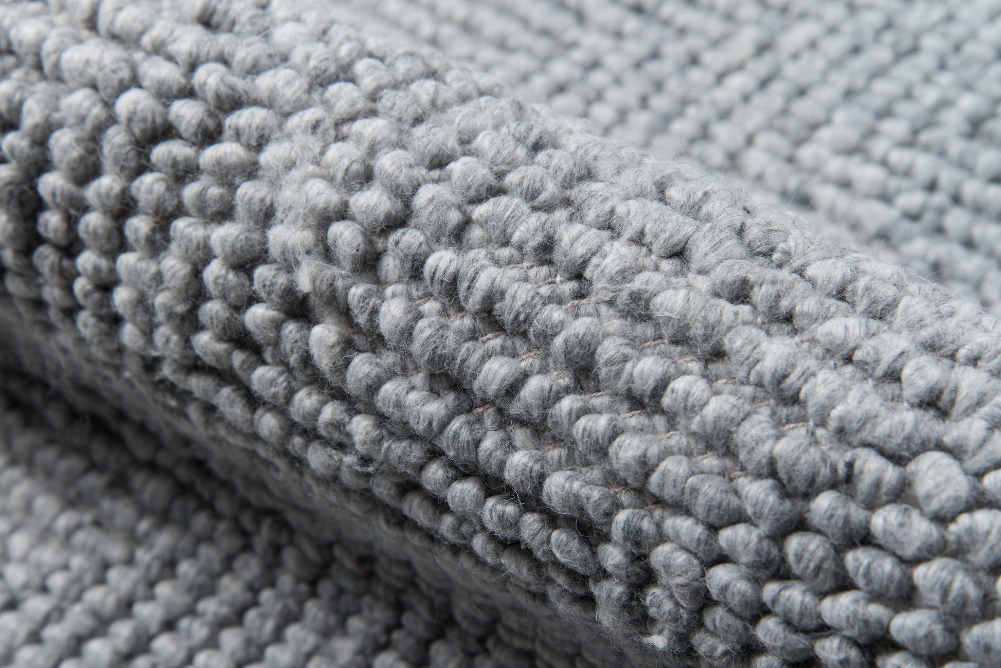 Close-up of soft grey boucle chenille fabric with dense looped pile, cozy home decor textile.
