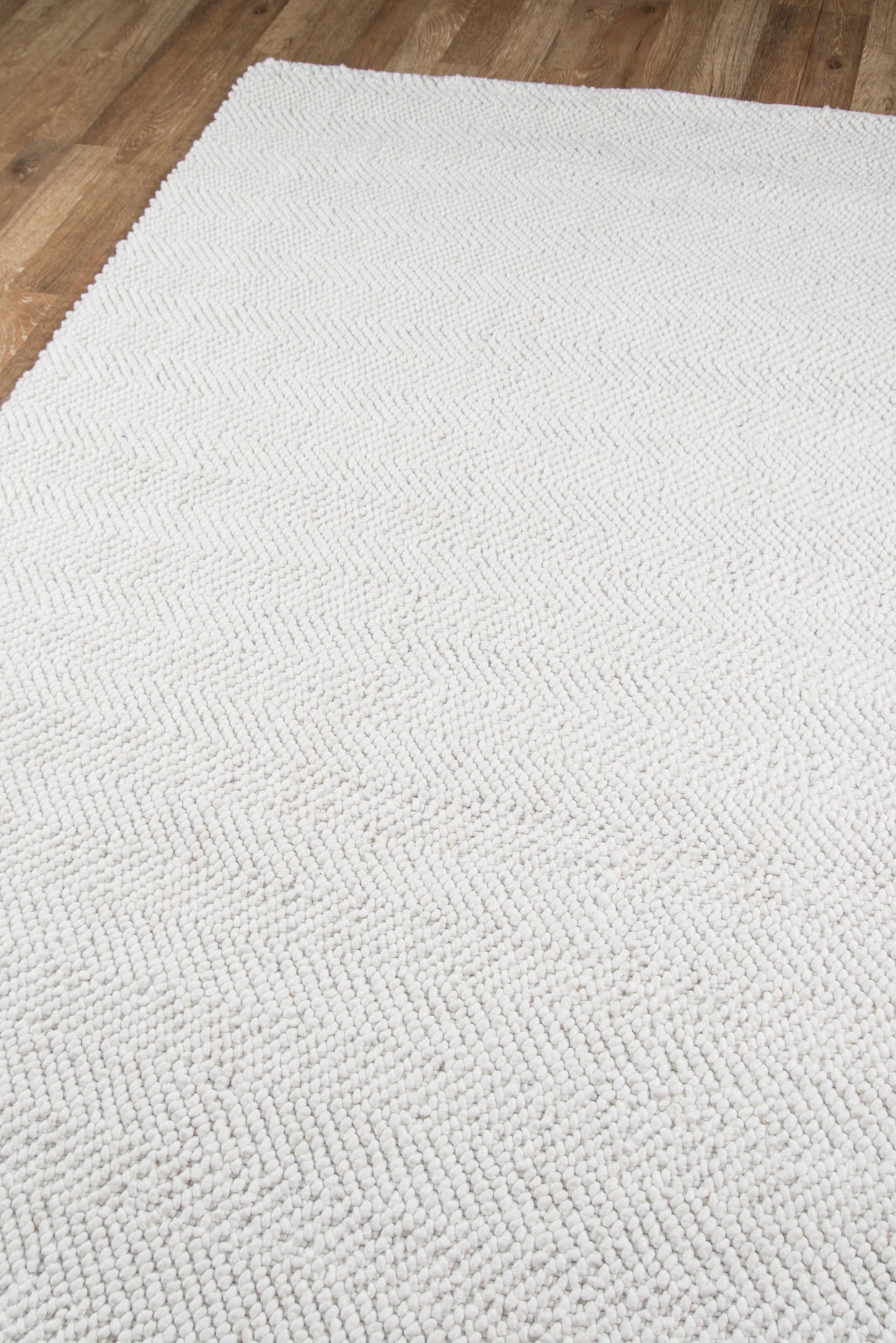 Ivory loop-pile area rug with chunky texture on wood floor.