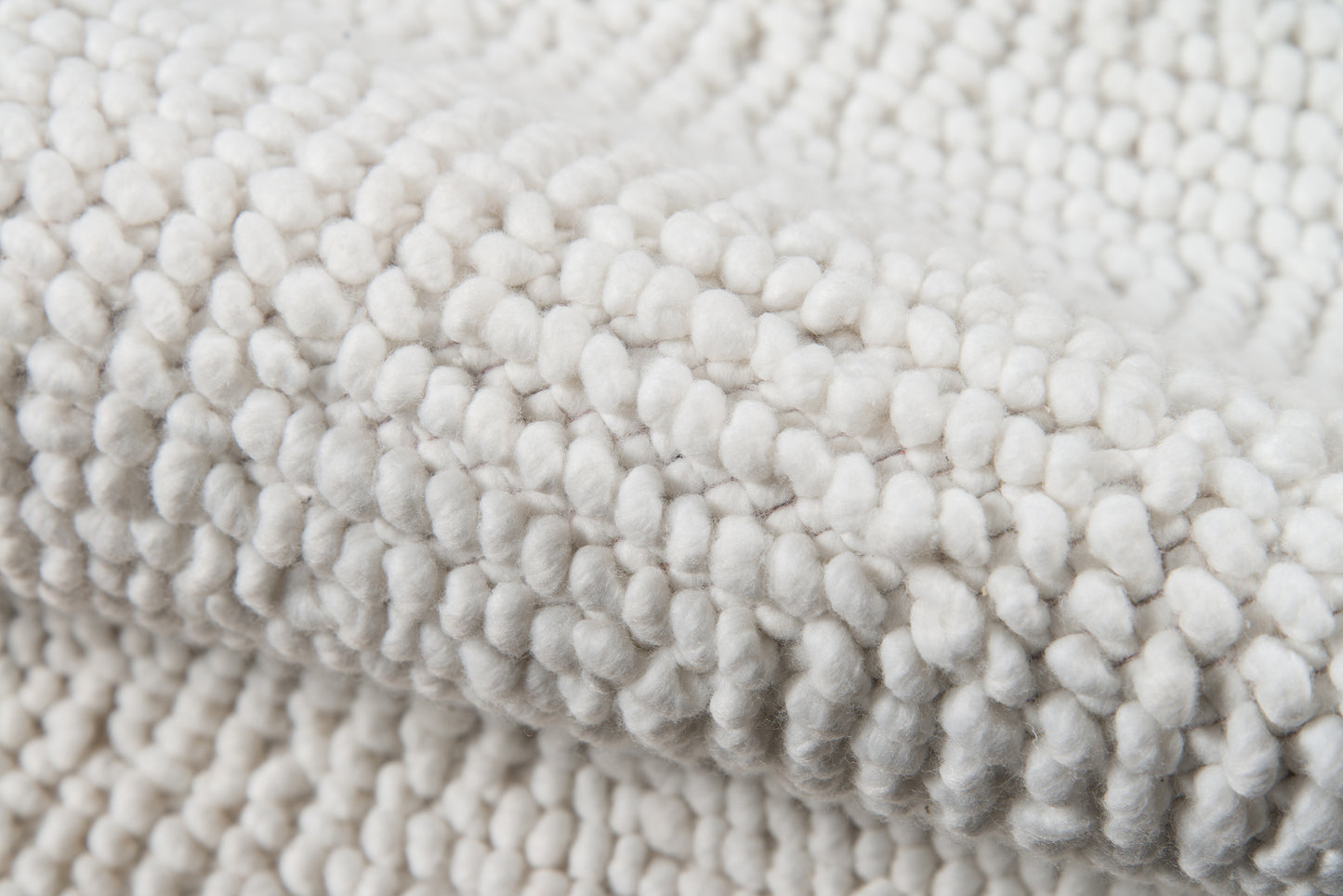 Ivory boucle rug close-up showing dense, plush pile of soft, looped fibers.