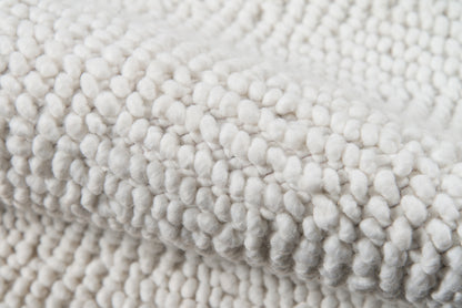 Ivory chunky-loop rug close-up with soft tufted pile and cozy texture.