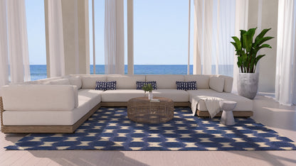 Ocean-view living room with white sectional, round wicker coffee table, navy-and-cream geometric runner rug & potted plant (3' x 8' runner).