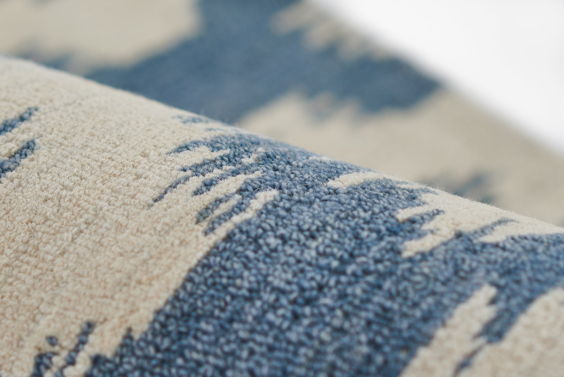 Close-up of a beige and blue woven rug with a soft pile and abstract stripe pattern.