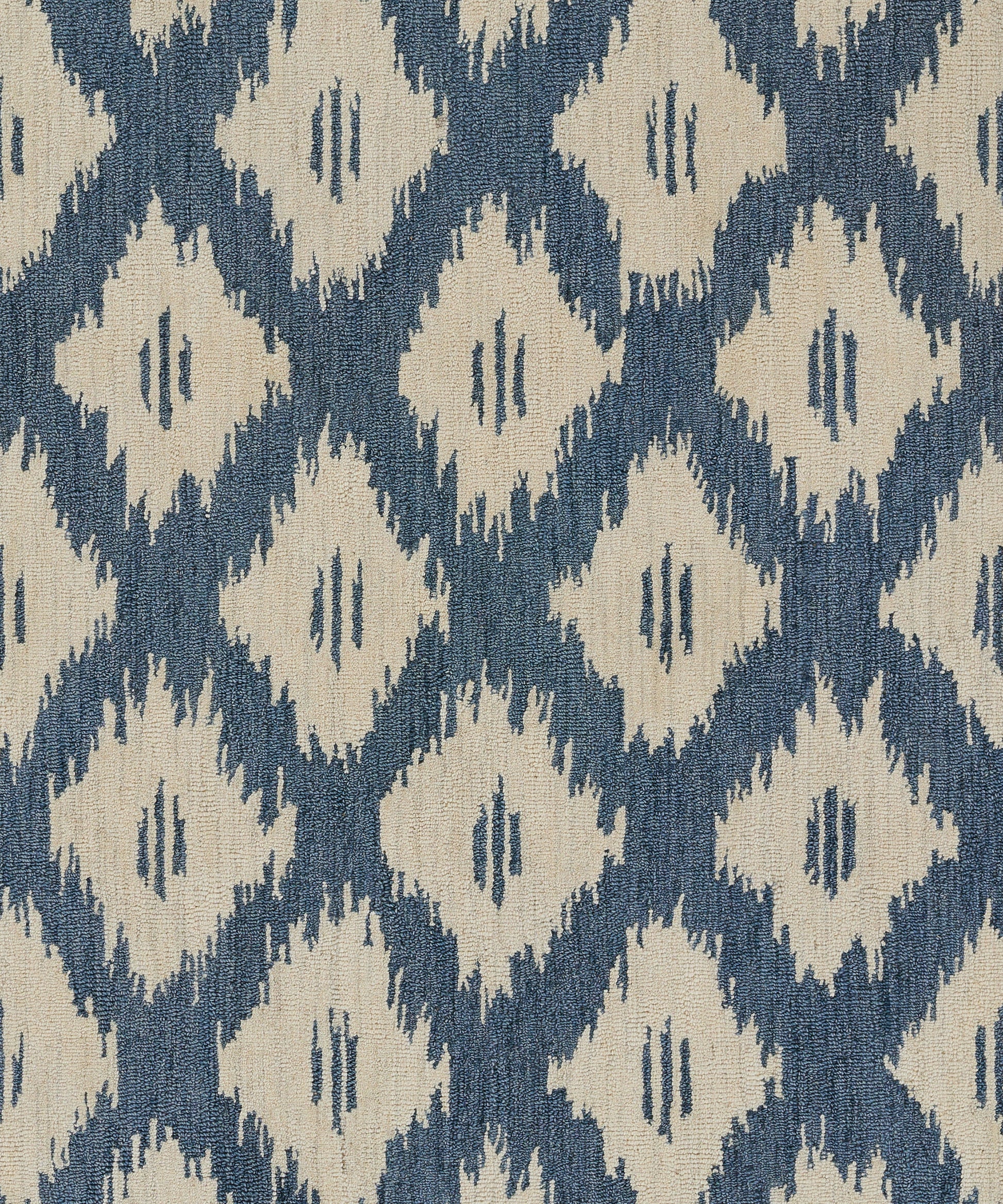 Blue background with beige diamond ikat pattern; woven rug fabric.