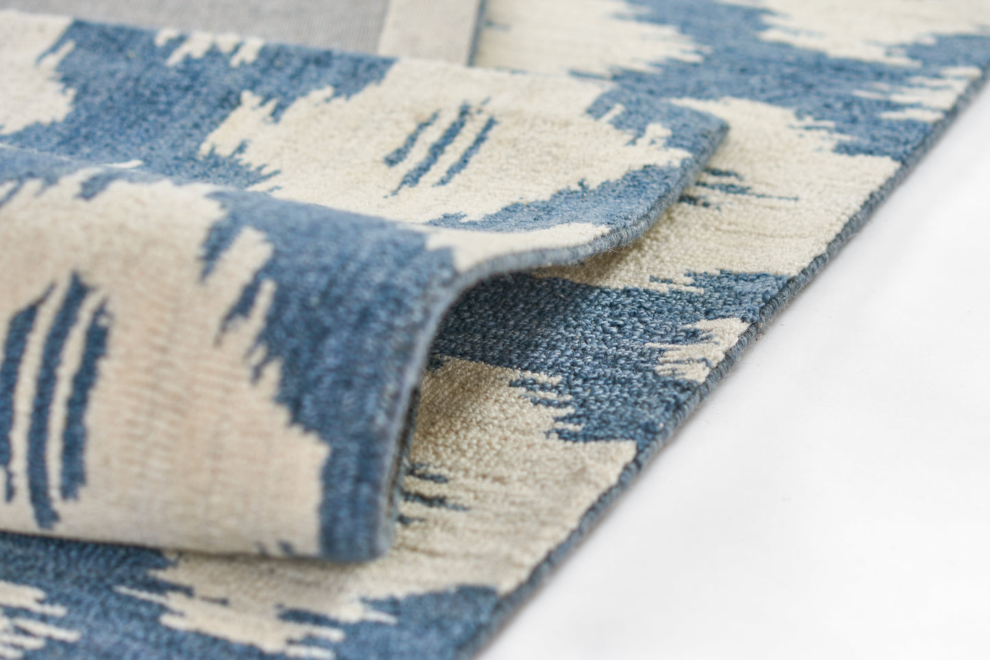 Blue and cream abstract patterned area rug with soft, plush pile and rolled edge