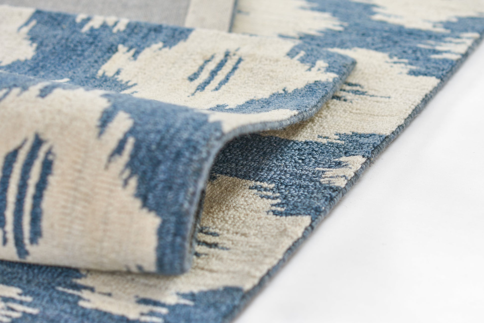 Blue and cream abstract patterned area rug with soft, plush pile and rolled edge