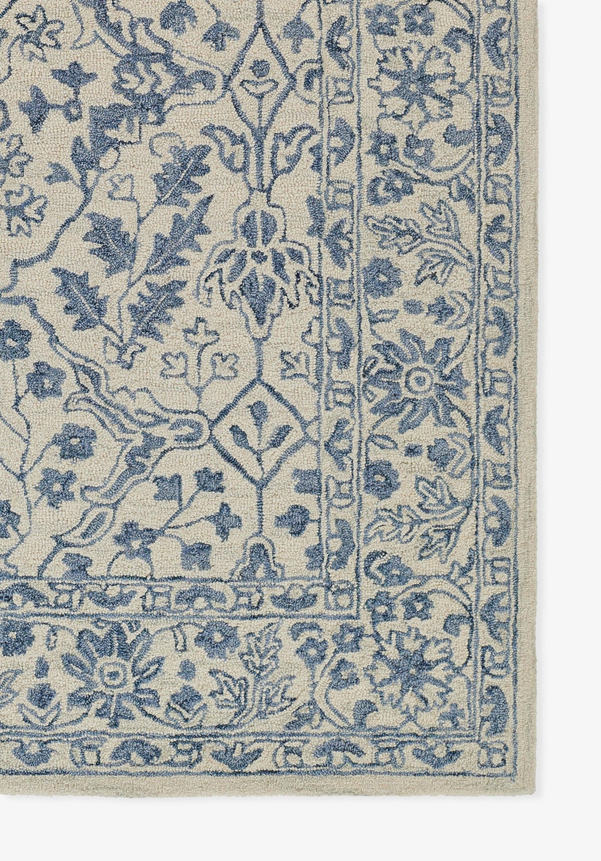 Beige area rug with blue intricate floral oriental pattern and bordered edge.